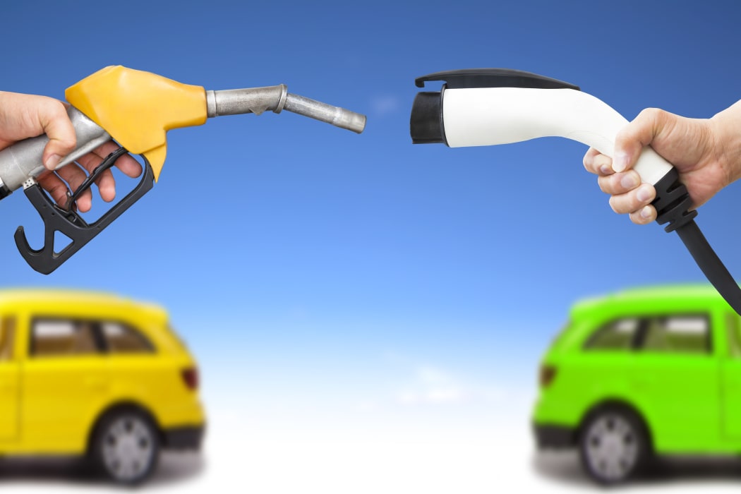 20231108 - electric car and gasoline car concept. hand holding gas pump and power connector for refuel