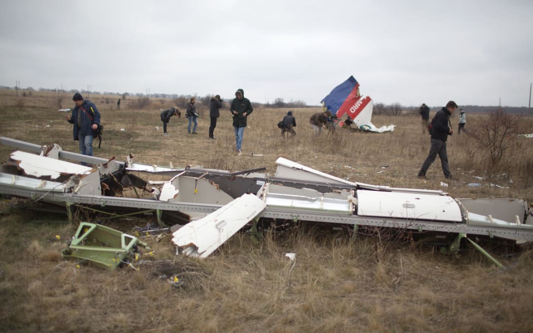 Journalists look at parts of the Malaysia Airlines plane Flight MH17 as Dutch investigators (unseen) arrive at the crash site near the Grabove village in eastern Ukraine on November 11, 2014