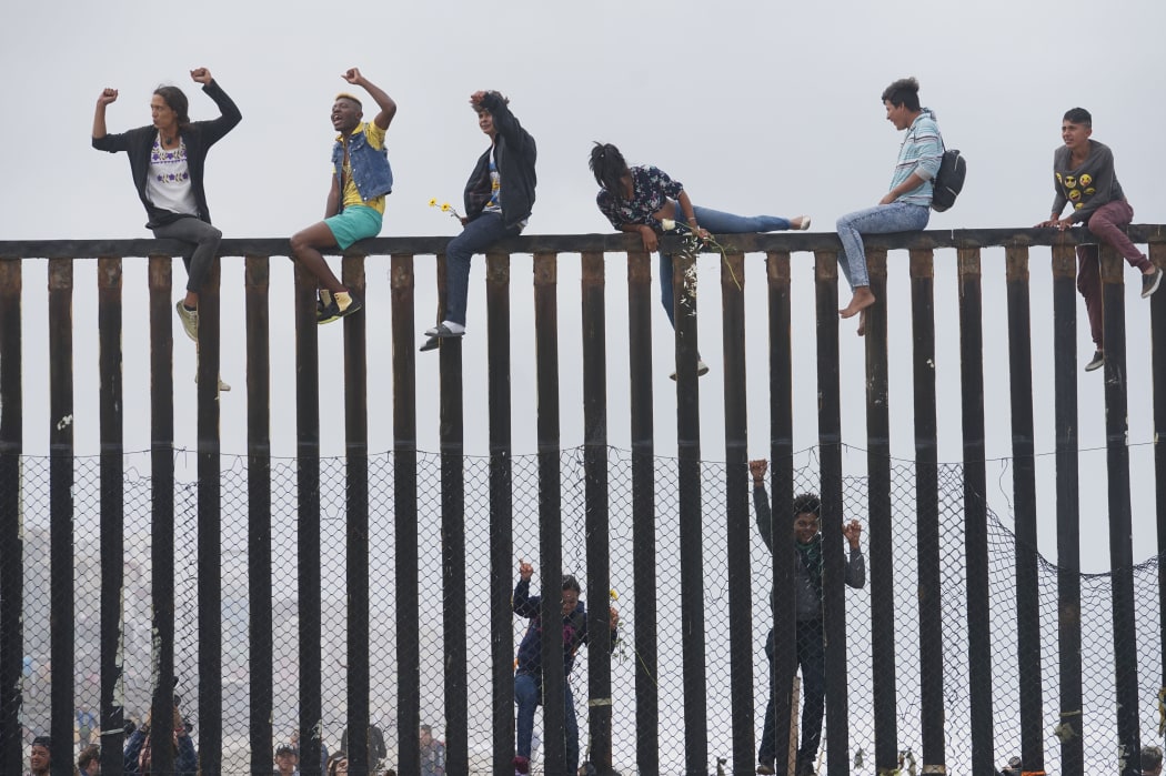 Migrant caravan demonstrators climb the US-Mexico border fence during a rally, on April 29, 2018, in San Ysidro, California.