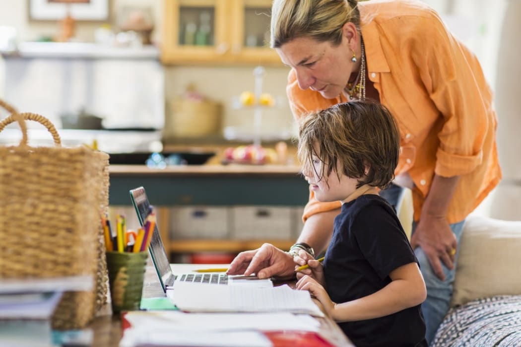 [New Mexico, United States] Adult woman helping her six year old son with a remote learning session on a laptop, using a touchpad.