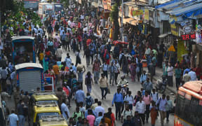 Commuters walk on a road outside a railway station in Mumbai on 26 April, 2023.
