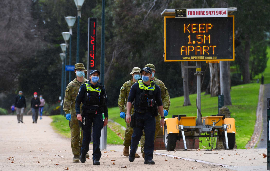 Police officers and soldiers patrol a popular running track in Melbourne on 4 August, 2020 after the state announced new restrictions as the city battles fresh outbreaks of the Covid-19 coronavirus.