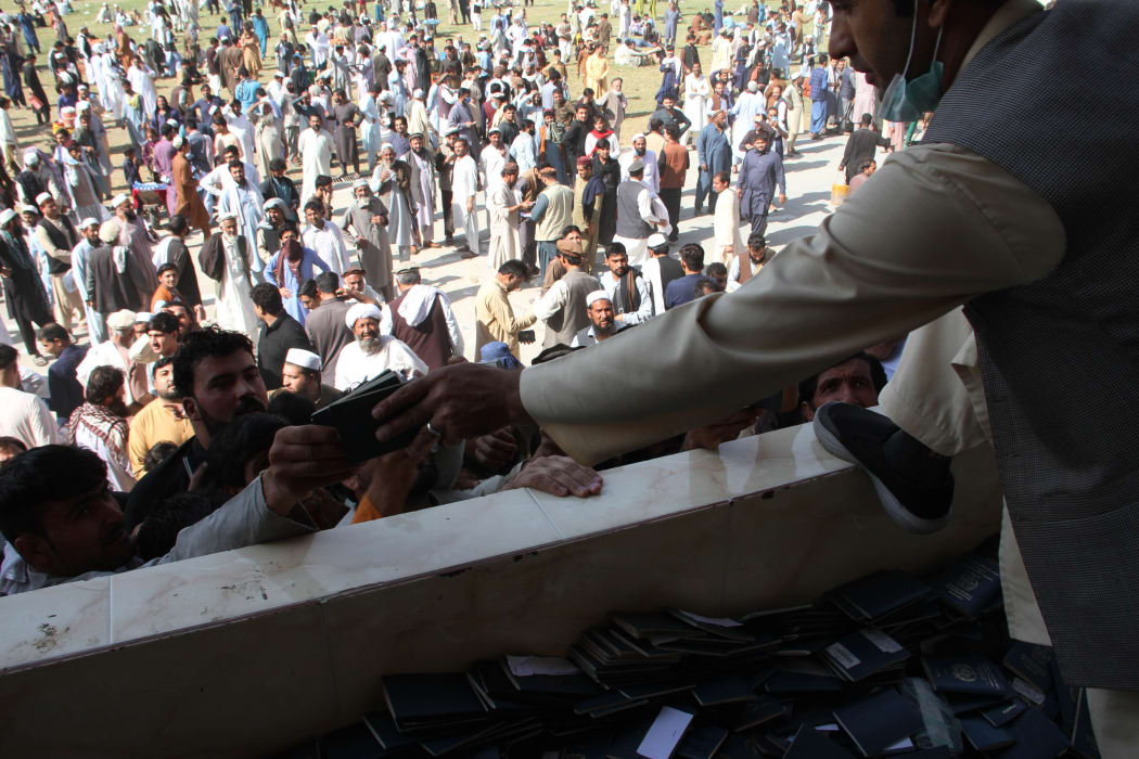 Afghans gather to collect token needed to apply for visas to Pakistan near the Pakistani consulate at an open stadium in Jalalabad city, Afghanistan.