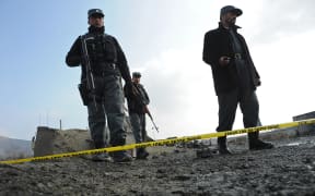 Afghan police stand guard at the site of a suicide attack near a NATO military convoy entering Kabul airport on December 11, 2013.