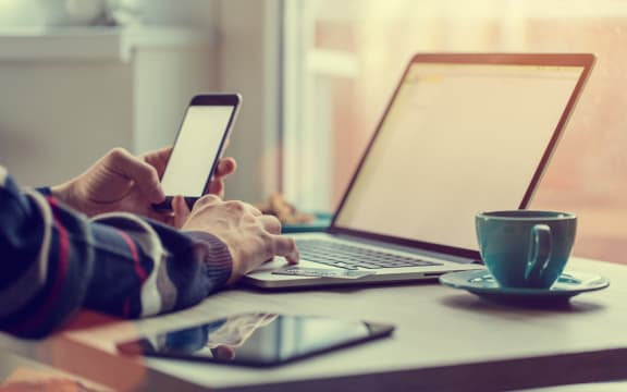 Man working on notebook, with a fresh cup of tea or coffee. Home work concept.