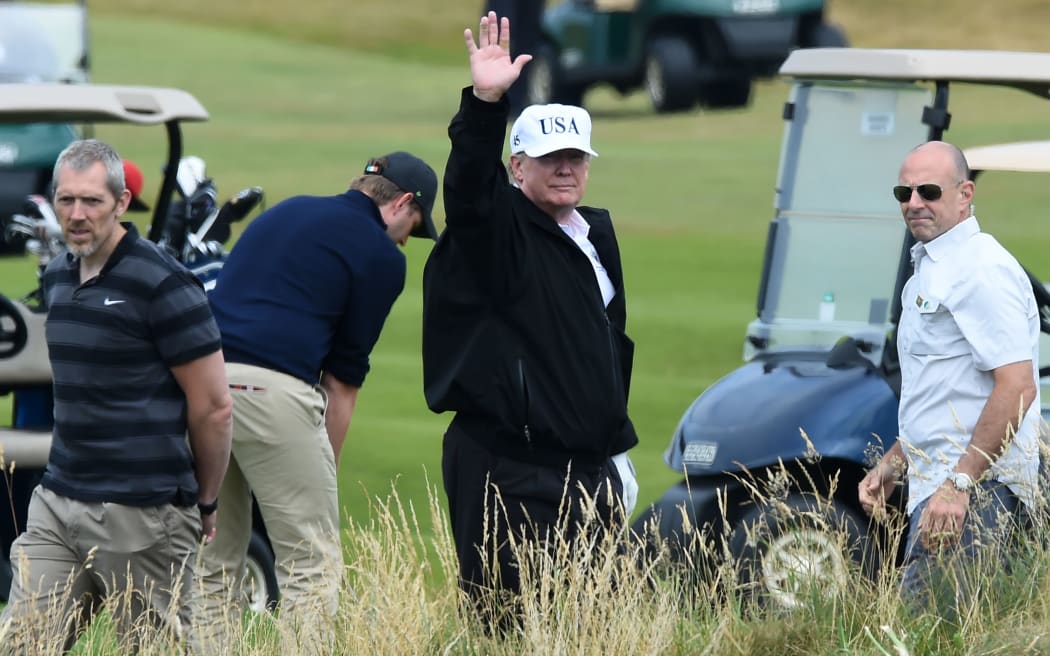US President Donald Trump (C) gestures as he walks during a round of golf on the Ailsa course at Trump Turnberry, the luxury golf resort of US President Donald Trump, in Turnberry, southwest of Glasgow, Scotland, during the private part of his four-day UK visit.