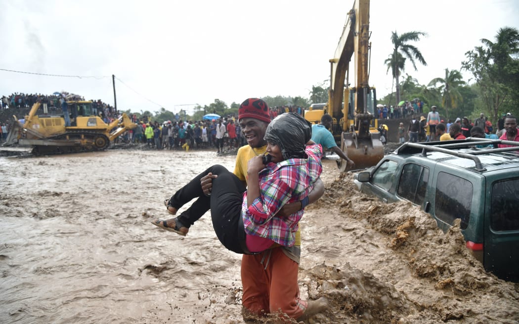 A woman is carried across the river La Digue in Petit Goave where the bridge collapsed during the heavy rain, southwest of Port-au-Prince.