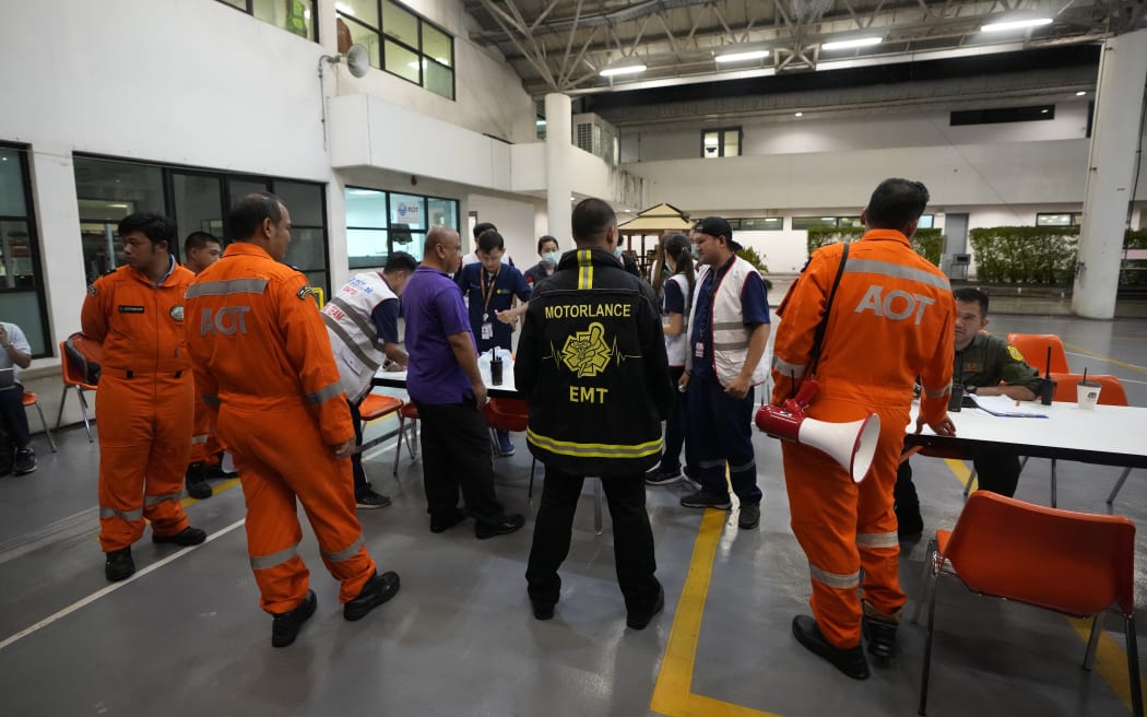 Members of a rescue team discuss after a London-Singapore flight was diverted to Bangkok due to severe turbulence, in Bangkok, Thailand, Tuesday, May 21, 2024. The plane apparently plummeted for a number of minutes before it was diverted to Bangkok, where emergency crews rushed to help injured passengers amid stormy weather, Singapore Airlines said Tuesday. (AP Photo/Sakchai Lalit)