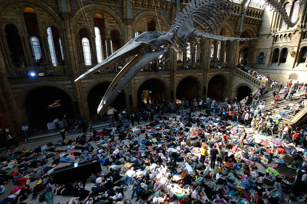 Extinction Rebellion climate change activists perform a mass "die in" under the blue whale in the foyer of the Natural History Museum.