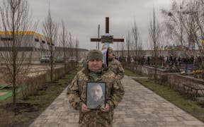 A Ukrainian soldier carries a portrait of late Ukrainian serviceman Andriy Katanenko, 39, who was killed near Avdiivka, during a funeral ceremony in Bucha, northwest of Kyiv, on February 24, 2024, on the second anniversary of Russia's invasion of Ukraine. (Photo by Roman PILIPEY / AFP)