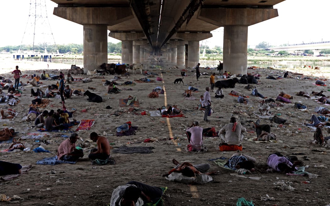 People take rest under a bridge at the Yamuna River bed on a hot summer day in New Delhi, India on 10 May 2022.