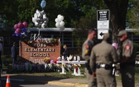 Police stand next to a makeshift memorial outside Robb Elementary School two days after 19 children and two teachers were killed at the elementary school in Uvalde, Texas, on 24 May.