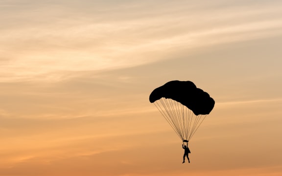Silhouette of a parachute against a background sunset.
