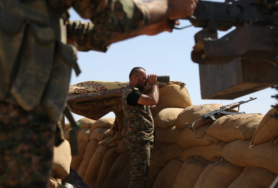 A Kurdish fighter uses binoculars on the front line in the northeastern Syrian city of Hasakeh. The US plans to send 250 more troops to encourage more people to join the Kurdish fighters.