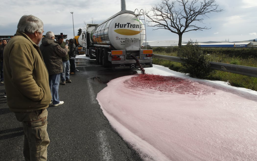 French winemakers watch wine flow from the tap of a Spanish truck's tanker on 4 April in France near the Spanish border during a demonstration of French winemakers against southern countries' wine imports.