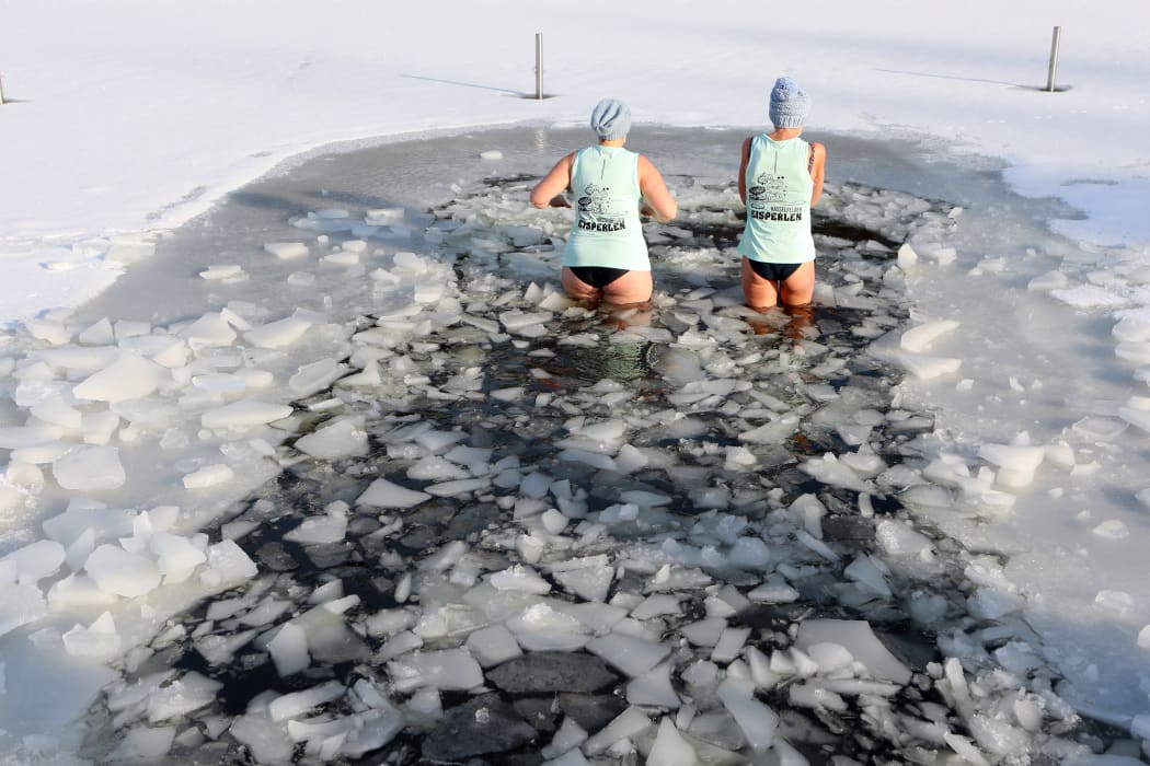 31 January 2021, Saxony-Anhalt, Hasselfelde: Two women get into the icy water in the Waldseebad.