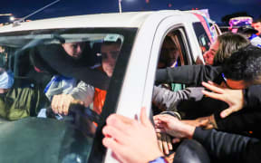 Emily Damari (L) reaches to shake hands with her friends while being transported with two other hostages upon arriving at Sheba Tel HaShomer Medical Centre in Ramat Gan on January 19, 2025, following their release from captivity by Hamas in the Gaza Strip after the October 7 attacks. The first three Israeli hostages were released on January 19 under a long-awaited Gaza truce aimed at ending more than 15 months of war that has ravaged the Palestinian territory. (Photo by Jack GUEZ / AFP)