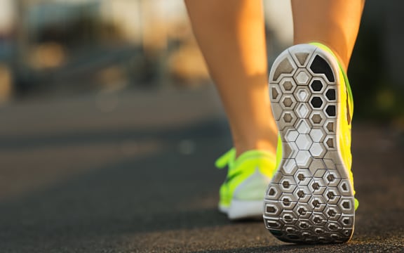 Woman runner showing feet and running shoes on track or road.