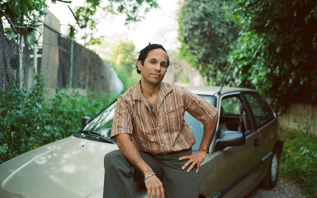 Multi-instrumentalist and producer Pachyman sitting on an 80s Honda in a retro shirt.
