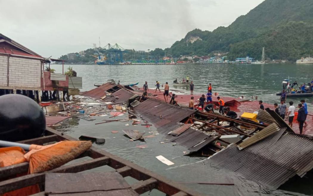 People stand on the roofing of collapsed shops in the port after a 5.2-magnitude earthquake in Jayapura.