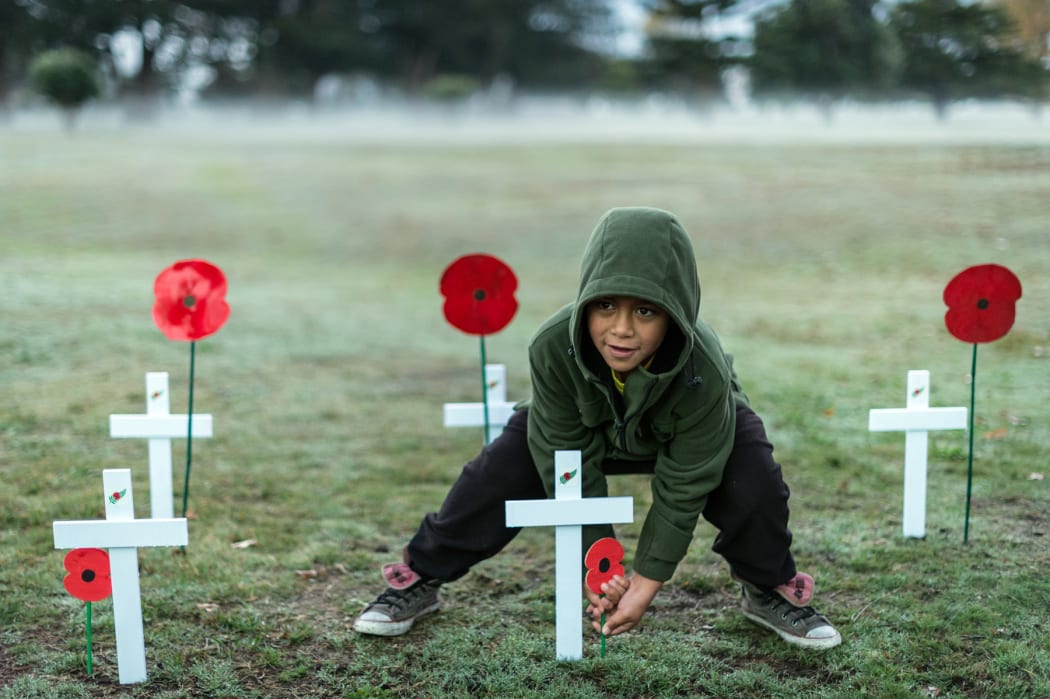 A child places a poppy at the dawn service at Tolaga Bay, near Gisborne.