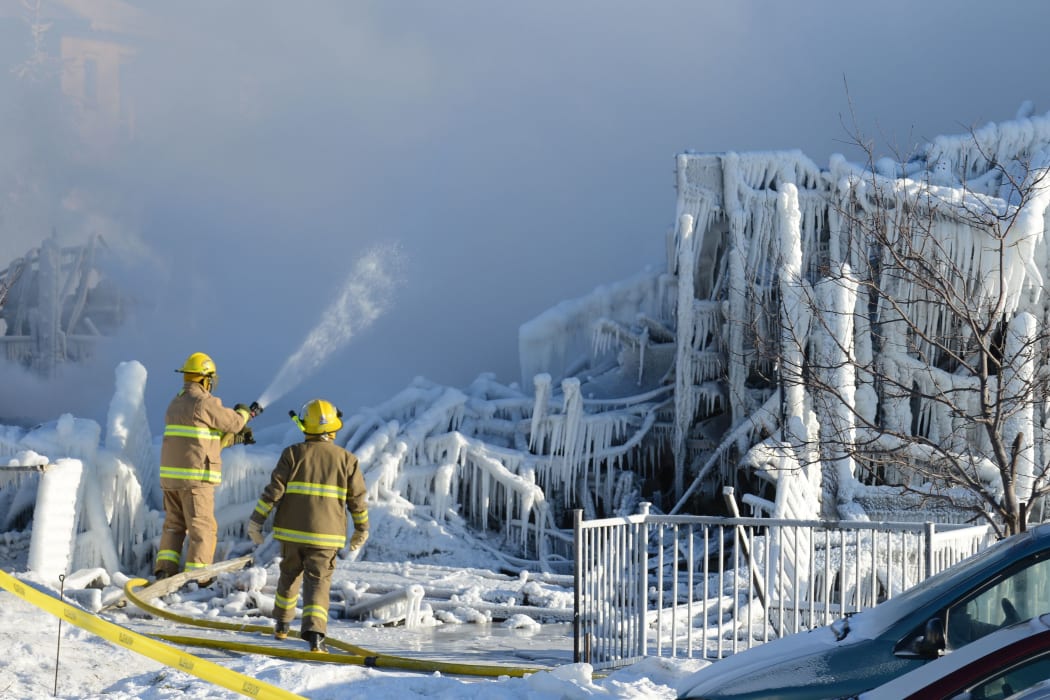 Canadian firefighters douse the burnt remains of a retirement home in L'Isle-Verte.