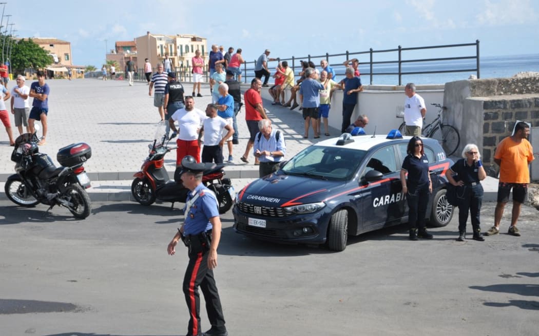 Italian Carabinieri patrol the port as the search continues for six passengers missing from a sailboat that sank off the coast of Porticello, north-western Sicily, on 19 August 2024. One person was killed and rescuers were searching for six others missing after a luxury superyacht "Bayesian" with 22 people aboard sank during a sudden storm.