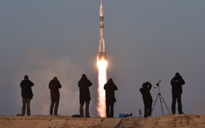 Photographers take pictures as Russia's Soyuz spacecraft blasts off.