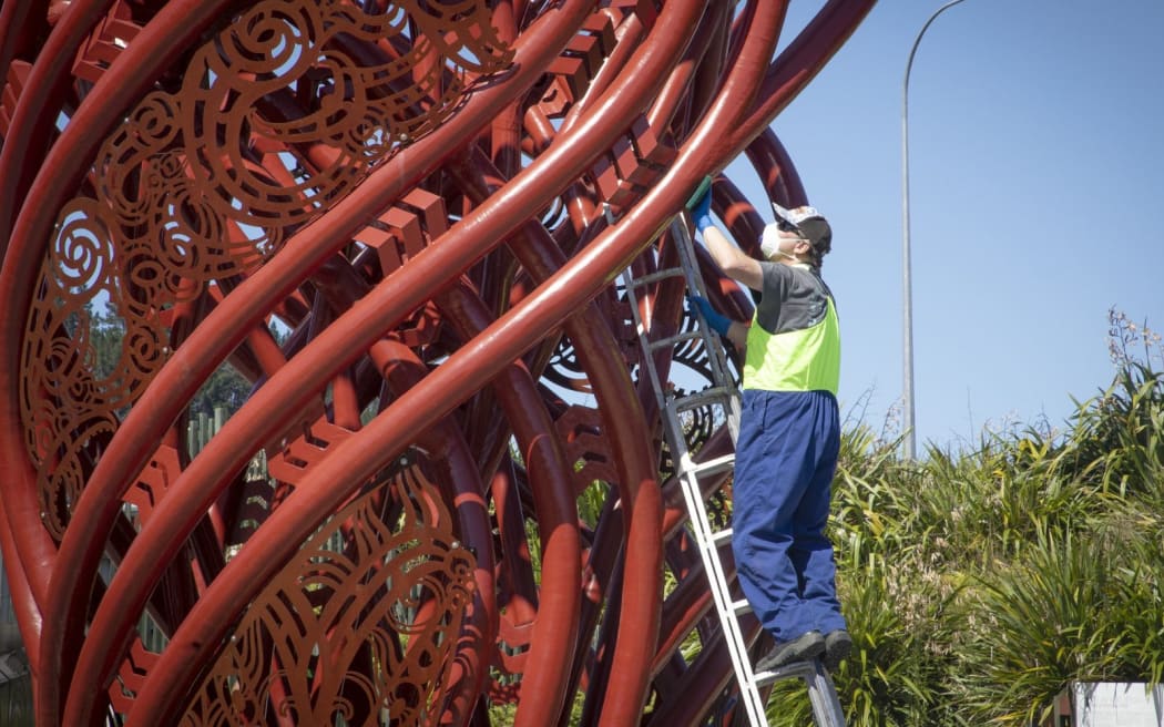 A man fixes the Hemo Gorge roundabout sculpture.