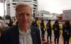 Grant Baildon stands in front of Amnesty International protesters in Auckland.