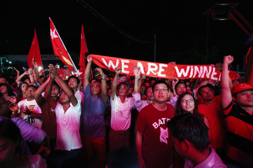Supporters of Myanmar opposition leader Aung San Suu Kyi's party cheer as they watch polling station counts on a giant screen outside the party headquarters in Yangon.