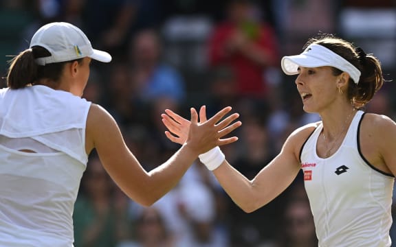 Poland's Iga Swiatek (L) shakes hands with France's Alize Cornet after their women's singles tennis match on the sixth day of the 2022 Wimbledon Championships at The All England Tennis Club in Wimbledon, southwest London, on July 2, 2022. (Photo by Glyn KIRK / AFP) / RESTRICTED TO EDITORIAL USE