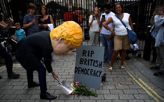 A man wearing a mask of Boris Johnson protests outside Downing Street over Parliament's suspension.