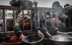Displaced Palestinian children gather to receive food at a government school in Rafah in the southern Gaza Strip on February 19, 2024, amid the ongoing battles between Israel and the militant group Hamas. (Photo by MOHAMMED ABED / AFP)
