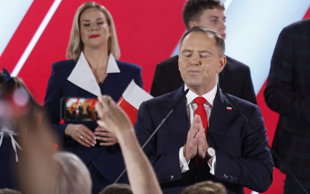 Karol Nawrocki, candidate for the 2025 Polish presidential election supported by Poland's right-wing Law and Justice (PiS) party, gestures as he addresses supporters as exit polls were announced during their election night event at the Mala Warszawa Theatre in Warsaw, Poland, during the second round of the presidential elections on June 1, 2025. The centrist and nationalist candidates in Poland's presidential election on June 1 both claimed victory after an exit poll indicated they were neck and neck. (Photo by Wojtek RADWANSKI / AFP)