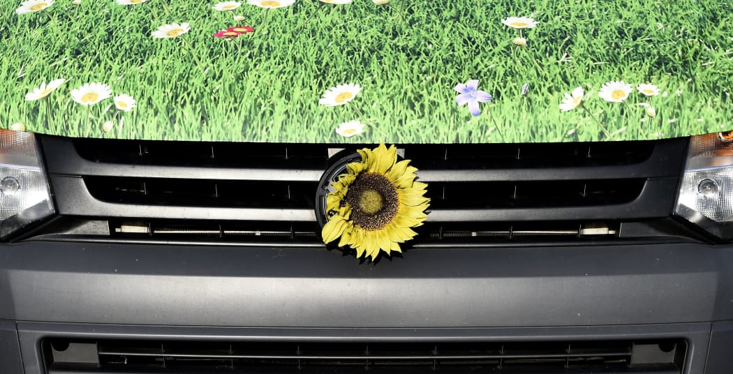 A sunflower decorates a "green" VW electric car at a service station in Berlin.