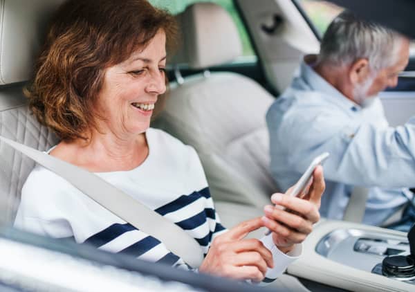 A midlife woman smiles at her phone while a man looks away.