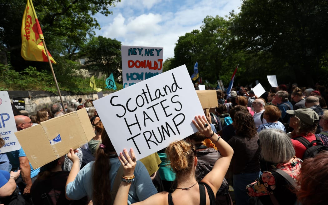 Demonstrators hold placards during a 'Stop Trump Coalition' protest near the US Consulate building in Edinburgh, Scotland on July 26, 2025. US President Donald Trump landed in Scotland on July 25, for a five-day visit set to mix diplomacy, business and leisure. (Photo by SCOTT HEPPELL / AFP)