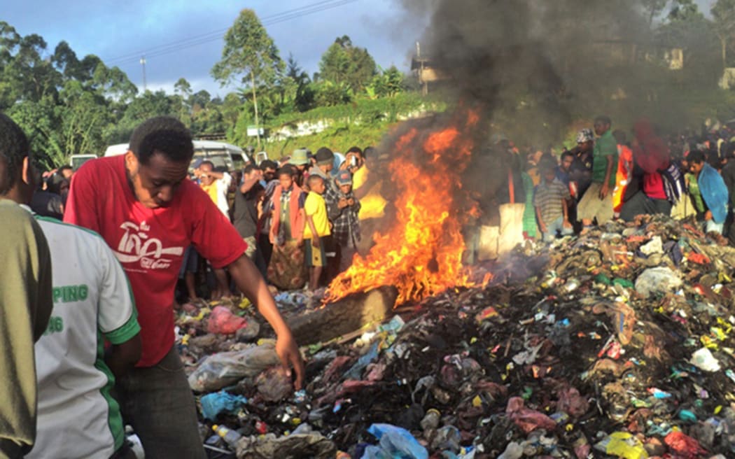 A photo taken on February 6, 2013 shows a crowd watching as a young mother accused of sorcery, is stripped naked, reportedly tortured with a branding iron, tied up, splashed with fuel and set alight on a pile of rubbish topped with car tyres, in Mount Hagen city in the Western Highlands of PNG.