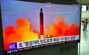 People walk past a television screen reporting news of North Korea's latest Musudan missile test, at a railway station in Seoul on June 23, 2016.