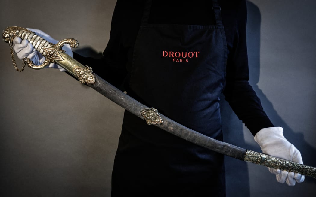 This photograph taken in Paris on April 25, 2025 shows the last sword that belonged to French Emperor Napoleon before its auction on May 22 at Hotel Drouot. The Giquello's auction house unveils the flagship lot of the next edition of Tentation, the sword Napoleon commissioned for his personal use from the great harquebusier Nicolas-Noel Boutet in 1802. The Emperor kept it until the end of his reign, before giving it to Emmanuel de Grouchy, the last Marshal of the Empire. Kept since 1815 by the marshal's descendants, it will be auctioned for the first time on 22 May at Hotel Drouot. (Photo by STEPHANE DE SAKUTIN / AFP)