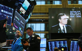 Traders work on the floor of the New York Stock Exchange (NYSE) as a picture of former President George H.W. Bush appears on a screen.