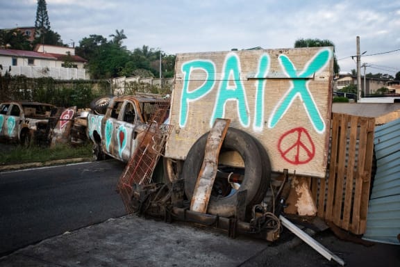 A photograph shows a roadblock set up by residents of Noumea's Sixth Kilometer district, bearing a handwritten message which reads as 'Peace' in Noumea, France's Pacific territory of New Caledonia on May 19, 2024. French forces smashed through about 60 road blocks to clear the way from conflict-stricken New Caledonia's capital to the airport but have still not reopened the route, a top government official said on May 19, 2024. (Photo by Delphine Mayeur / AFP)