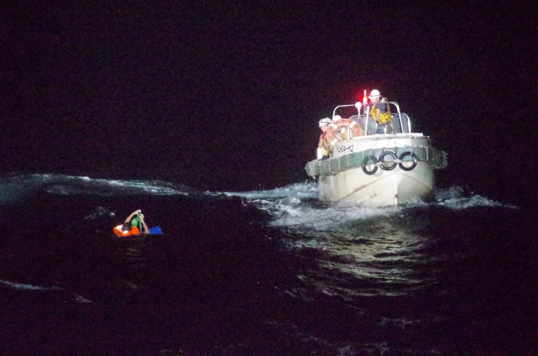 A man in the water with a rescue boat nearby.