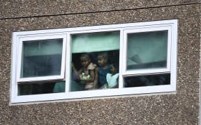 Residents look from a window at one of nine public housing estates locked down due a spike in COVID-19 coronavirus numbers in Melbourne on July 6, 2020.