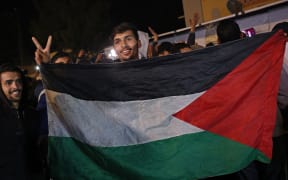 People celebrate along a street in Khan Yunis in the southern Gaza Strip on January 15, 2025, amid the ongoing war in the Palestinian territory between Israel and Hamas. Thousands of Gazans celebrated on January 15 as news spread that a ceasefire and hostage release deal had been reached between Israel and Hamas, aimed at ending more than 15 months of war in the Palestinian territory. (Photo by BASHAR TALEB / AFP)