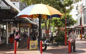 Summer in Wellington, Cuba Street. A man seeks shelter from the sun.