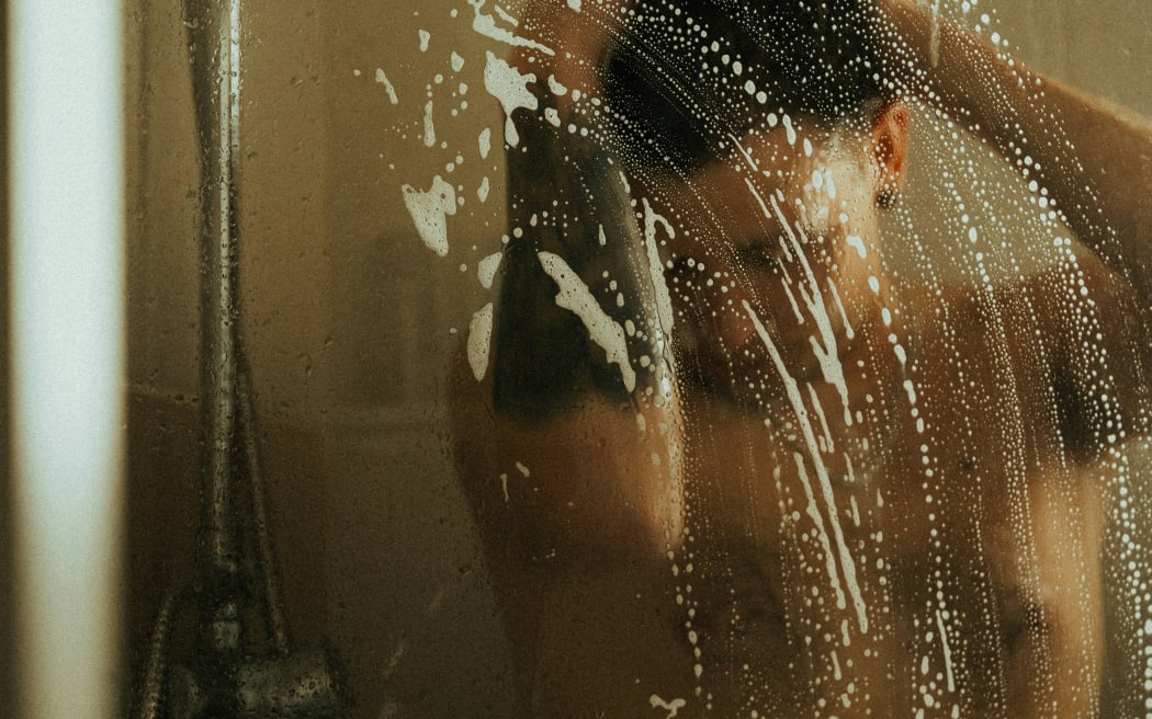A man behind a misty shower door.
