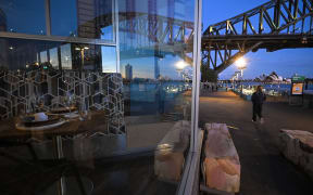 The Sydney Opera House and the Sydney Harbour Bridge are reflected in the window of a closed restaurant at Milson's Point, during lockdown in Sydney