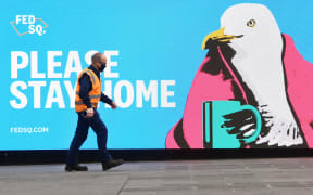 A man passes a sign encouraging people to stay home in Melbourne on May 28, 2021, as the city's residents returned to a seven day lockdown to curb the spread of the Covid-19 coronavirus. (Photo by William WEST / AFP)